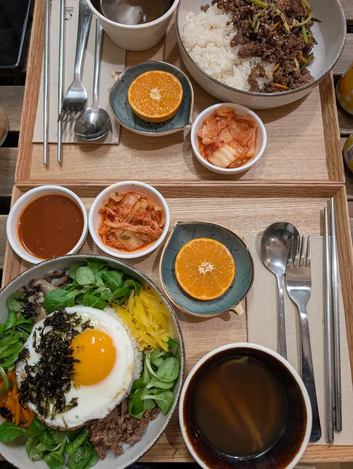 Bibimbap con huevo frito, verduras y ternera sobre arroz, con kimchi y naranja